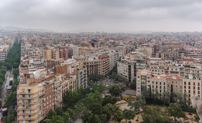 Fototapeta premium View to Barcelona city from the top of the basilica in a dull, murky day with a very grey and overcast sky. Barcelona skyline under heavy grey clouds.