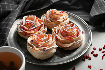 Metal tray with rose shaped apple pastry on table
