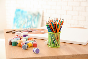 Gouache and pencils of professional artist on wooden table