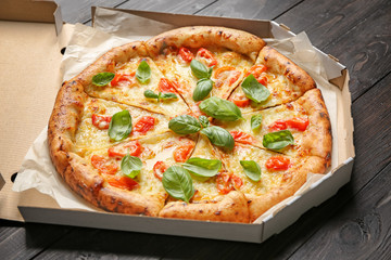 Carton box with delicious pizza Margherita on wooden background