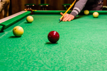 Player arm with the cue and balls on the green cloth. Russian billiard