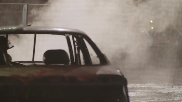 Driver in his Demo Derby Car, Smoking Engine, Tight Shot, Night