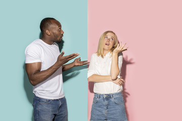 Beautiful female and male portrait on pink and blue studio backgroud. The young emotional couple