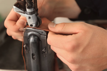 Man using sewing machine in leather workshop, closeup - obrazy, fototapety, plakaty