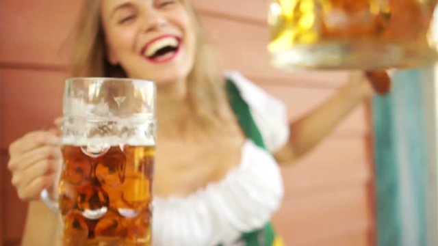 A sexy young lady drinks beer at a beer festival in Germany. Close-up, large beer mugs, a girl laughing cheerfully, red lips, white-toothed smile