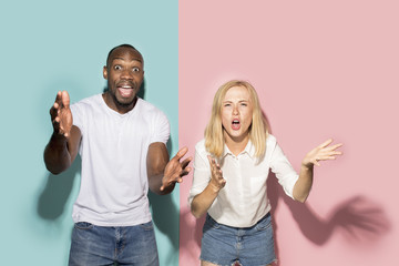 The afro surprised couple watching sports match on tv at home, successful game. Different emotions concept. Studio shot with african american man and woman