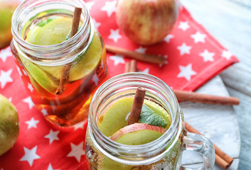 Tasty apple drink with cinnamon in mason jars on board