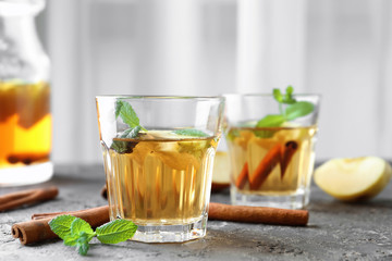 Apple drink with cinnamon in glass on table against light background