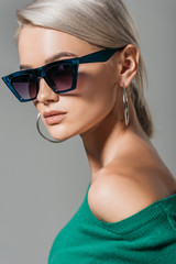 stylish female model in sunglasses looking at camera isolated on grey background