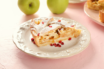 Plate with piece of delicious apple pie on light background
