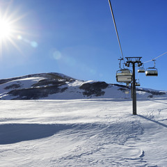 Chair-lift and blue sky with sun