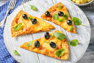 Slices of tasty pizza with olives on wooden board
