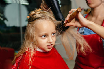 Woman cuts the baby hair. The girl is afraid to cut hair. He closed his eyes with fear. The background image place for text.