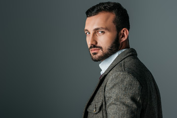 handsome confident man posing in tweed jacket, isolated on grey