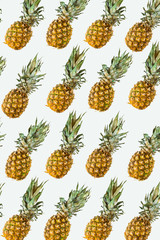 Isolated pineapples pattern or wallpaper on white background. Summer concept of fresh ripe whole pineapples shot from above