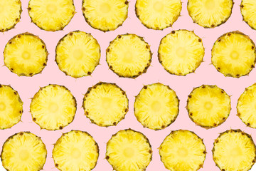 Sliced pineapple pieces lay in pattern on isolated light pink background. Freshly cut pineapple fruit on vivid background.