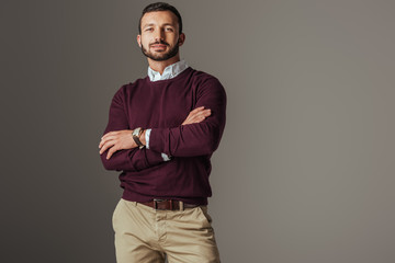 handsome man posing in burgundy autumn sweater with crossed arms, isolated on grey