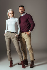 young couple posing in stylish autumn outfit, on grey