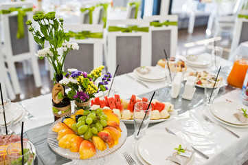 Wedding tables decorated with flowers and covered with huge variety of food.