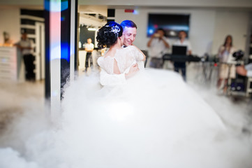 Fototapeta premium Romantic newly married couple performing their first dance in the restaurant with heavy smoke.