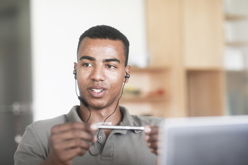 Junger Mann an einem Schreibtisch mit bluetooth headset