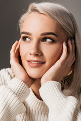 attractive stylish girl posing in white knitted sweater, isolated on grey