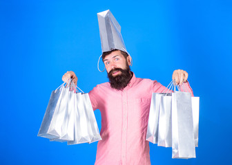 Hipster on smiling face with bag on head is addicted shopaholic. Shopping concept. Guy shopping on...