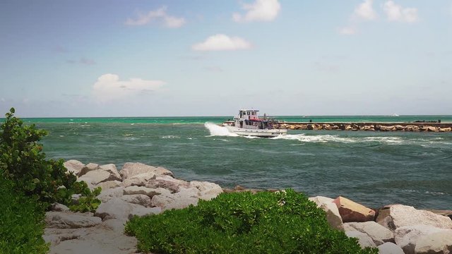 A boat leaving the Haulover Inlet along a jetty in Bal Harbour.