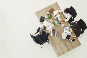 Three business woman discussing work on table in office, top view