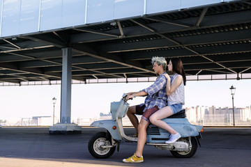 Fototapeta na wymiar young beautiful couple in love riding on old scooter. adventure and vacations concept. motorbike, summer, traveling, romance, smiling, happy, having fun, stylish outfit, date, enjoying in trip