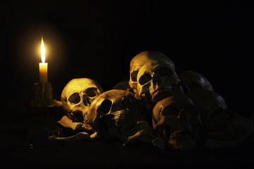 Still life style ;Skulls of bones with candle at night on back background.Halloween day