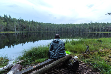 A fisherman is fishing on a forest lake