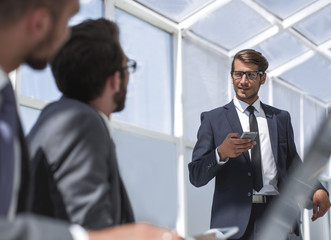 businessman with a smartphone standing in his ofiice