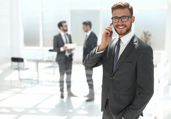 businessman with mobile phone standing next to the Bank office