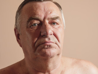 Aged man portrait on light background.