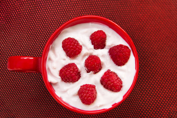 Yoghurt with raspberries on red texture