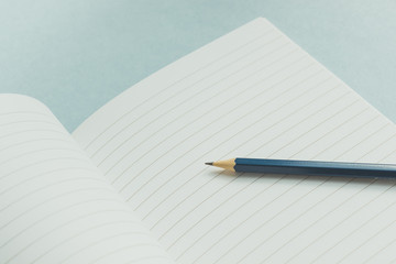 Notepad with clean sheets and a pencil on a blue pastel background. vintage colors. Back to school. Close up. Business, education concept. 