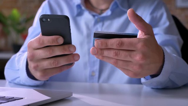 Close footage of man hands paying bills with credit card, purchasing through internet, sitting at table