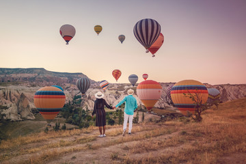 happy young couple during sunrise watching the hot air balloons of Kapadokya Cappadocia Turkey