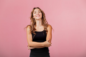 Portrait of young cheerful blonde woman wearing black dress against pink background