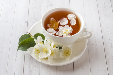 Mug of herbal tea with petals of Jasmine flowers on a light background.