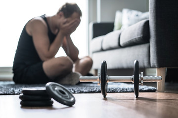 Workout problem, stress in fitness or too much training. Sad or tired man having trouble with overtraining. Exhausted and unhappy athlete with depression.
