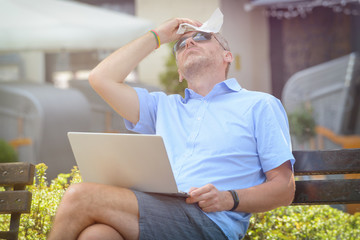 Man suffers from heat while working with laptop