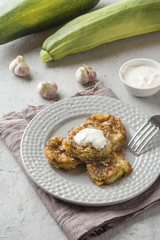 Fried zucchini slices in egg batter with garlic on a plate.