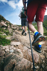 Man hiker walking on mountain rocks with sticks. Beautiful weather with Scotland nature. Detail of...