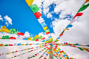 Looking up at Buddhist prayer flags. Tibetans believe the prayers and mantras will be blown by the...