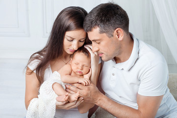 Woman and man holding a newborn. Mom, dad and baby. Close-up. Portrait of  smiling family with newborn on the hands. Happy family concept