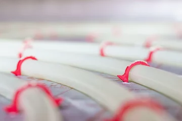 Close-up of flexible PVC tubing for heated flooring after completed custom installation © Tim