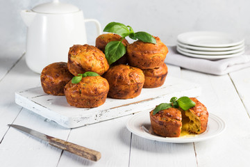 Homemade freefly baked double cheese muffins with basilic on a white wooden board. Healthy snack or breakfast meal. Concept of healthy eating in pure tones.