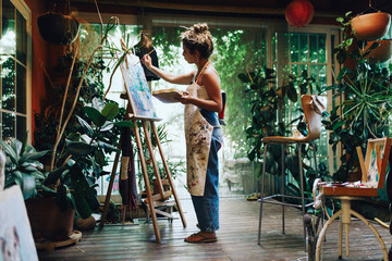 Woman drawing on a camvas in art studio - obrazy, fototapety, plakaty